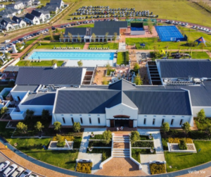 Large residential clubhouse with pools and tennis courts in a planned community.