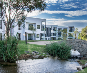 Modern apartment buildings beside a landscaped stream.