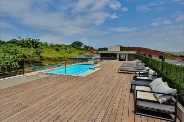 Rooftop pool deck with lounge chairs and hillside views.