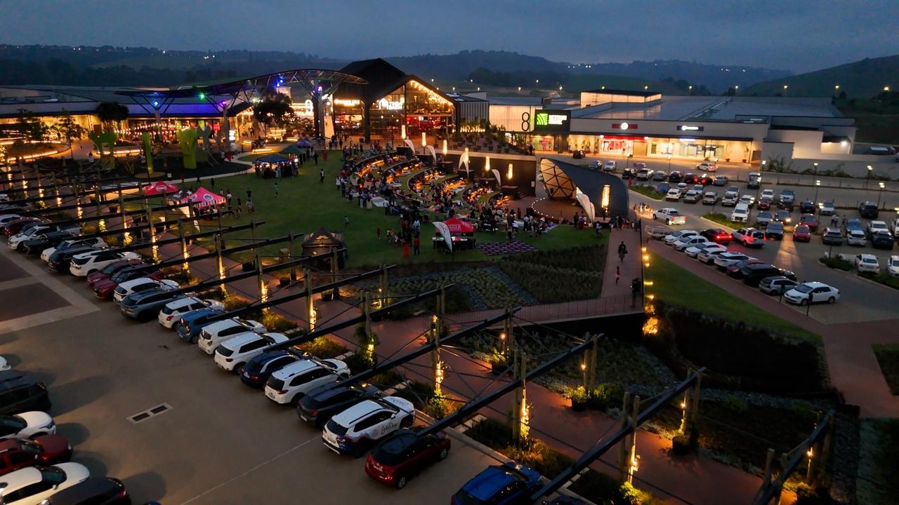 Westown Square outdoor event space with crowd and retail centre at dusk