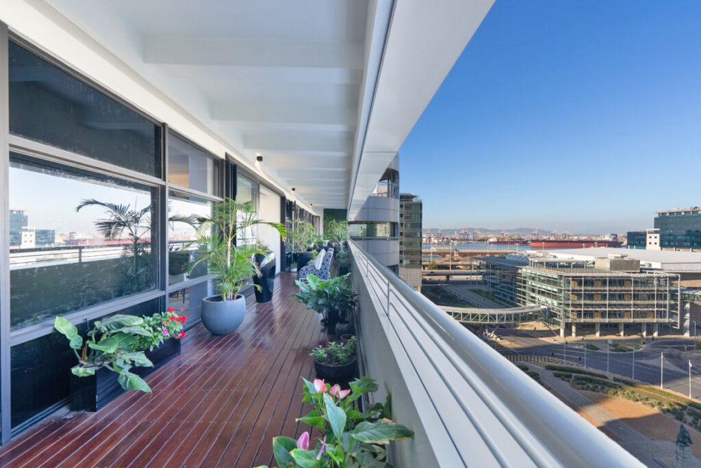 View north from a covered eleventh-floor balcony of the penthouse, looking over the Cape Town International Convention Centre to the working port and Table Bay