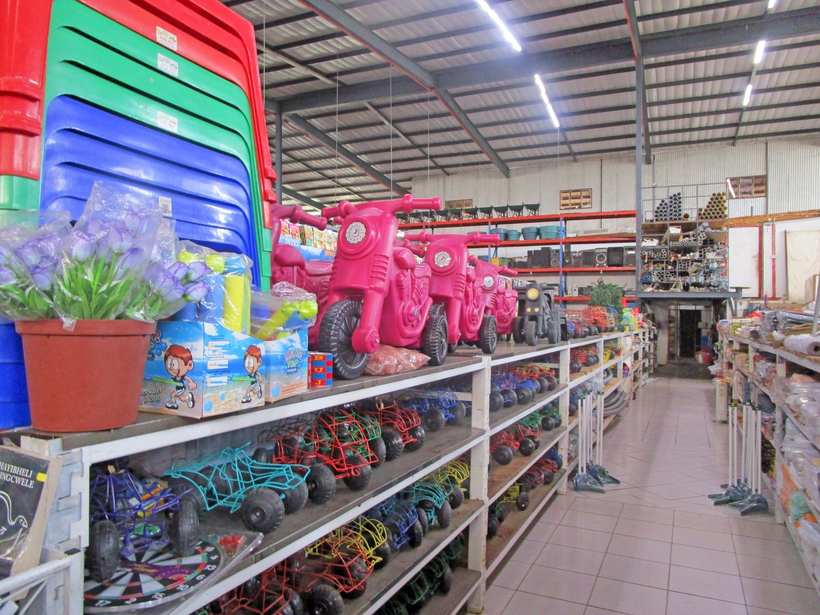 Shelving stacked with buckets, basins, plastic housewares and garden goods in the general retail warehouse.