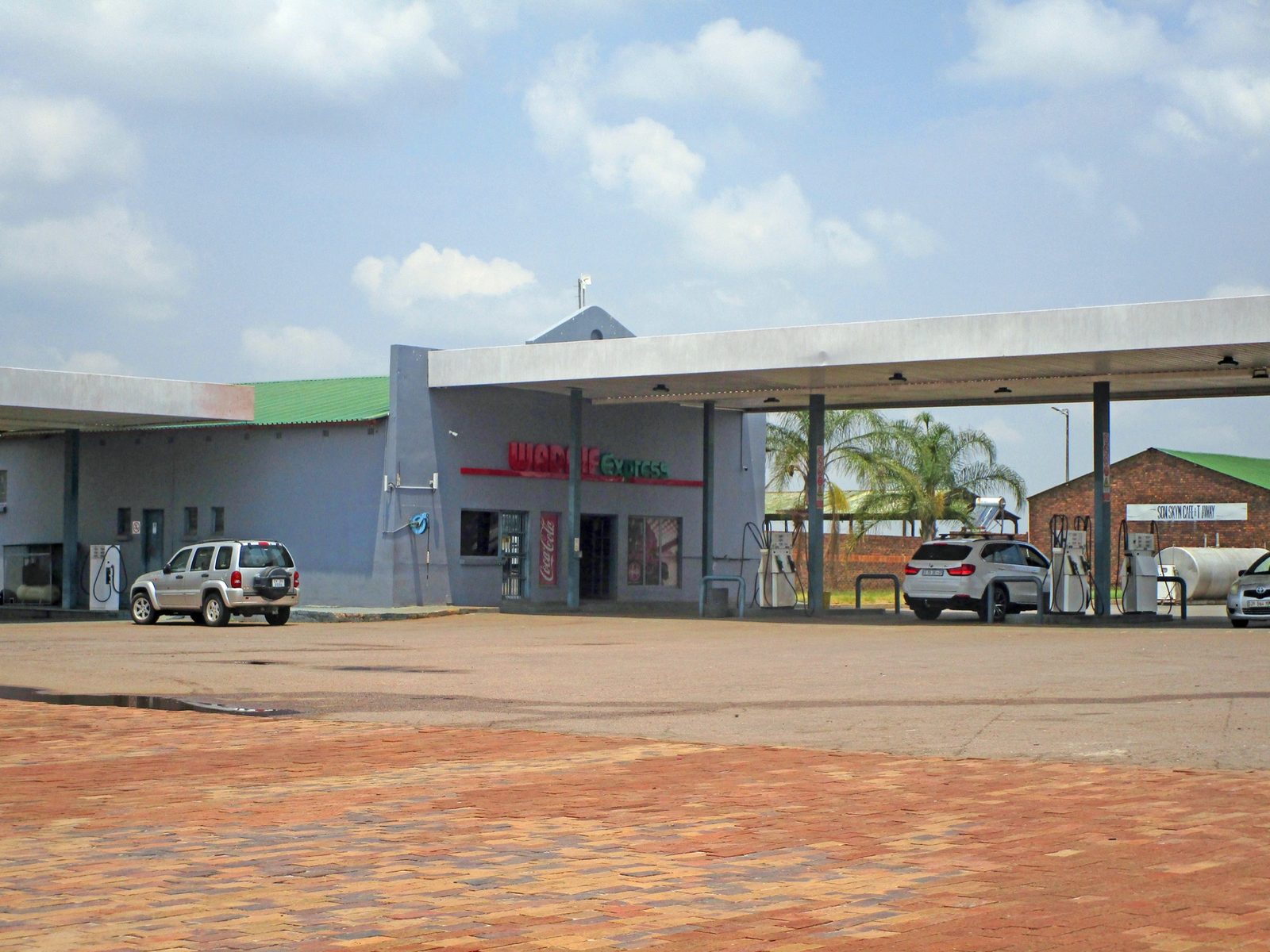 The filling station forecourt at Wadrif, with fuel pumps under a wide canopy, a paved apron and vehicles parked alongside.