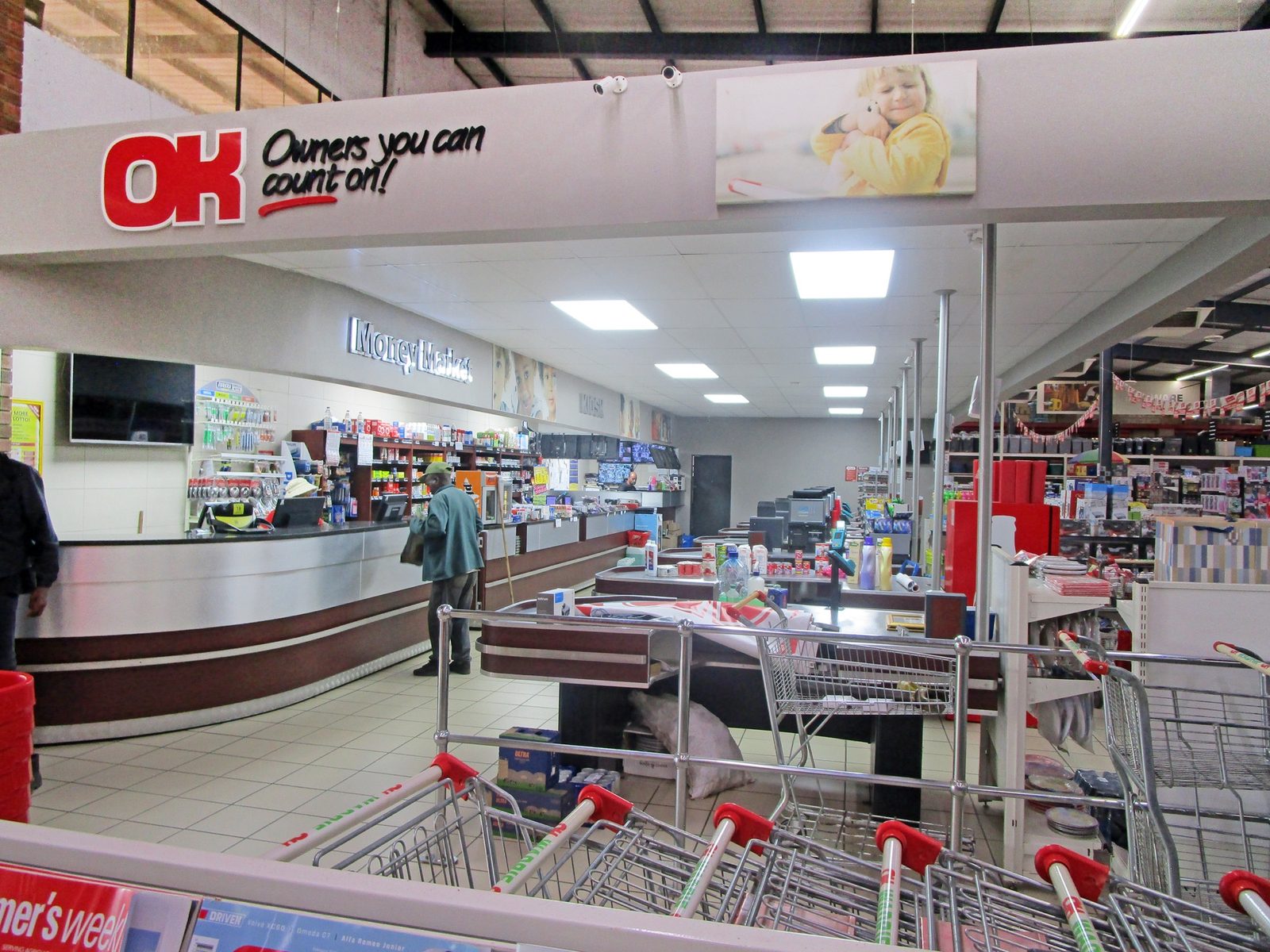 Checkout lanes inside the OK Grocer at Wadrif, with trolleys lined up and shoppers at the tills.