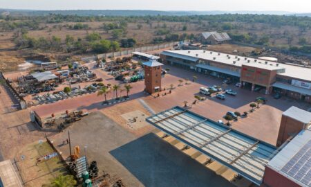 Aerial view of the Wadrif node showing long warehouse roofs, a loading yard with trucks and the retail frontage facing the R573.